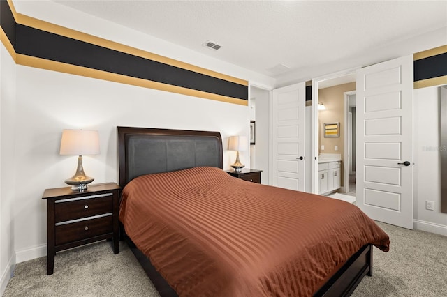 bedroom with connected bathroom and light colored carpet