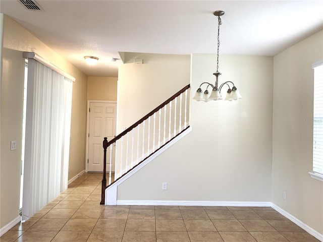 tiled foyer entrance with an inviting chandelier