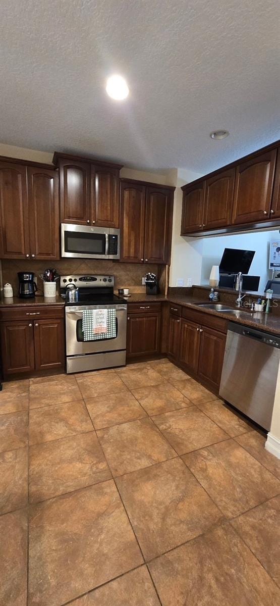 kitchen featuring appliances with stainless steel finishes, sink, a textured ceiling, and dark brown cabinets