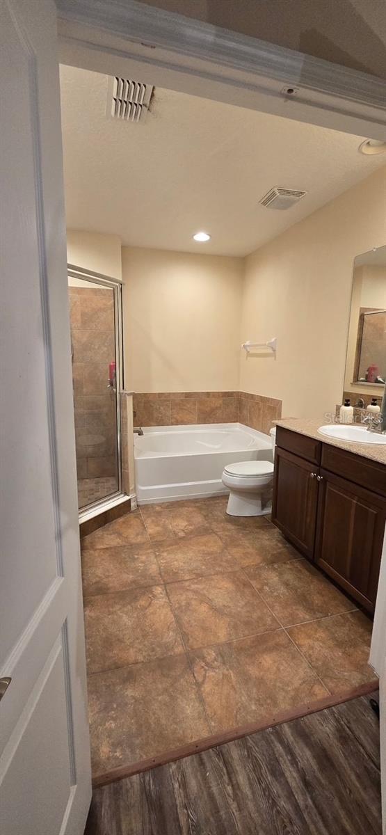 full bathroom with vanity, wood-type flooring, plus walk in shower, and toilet