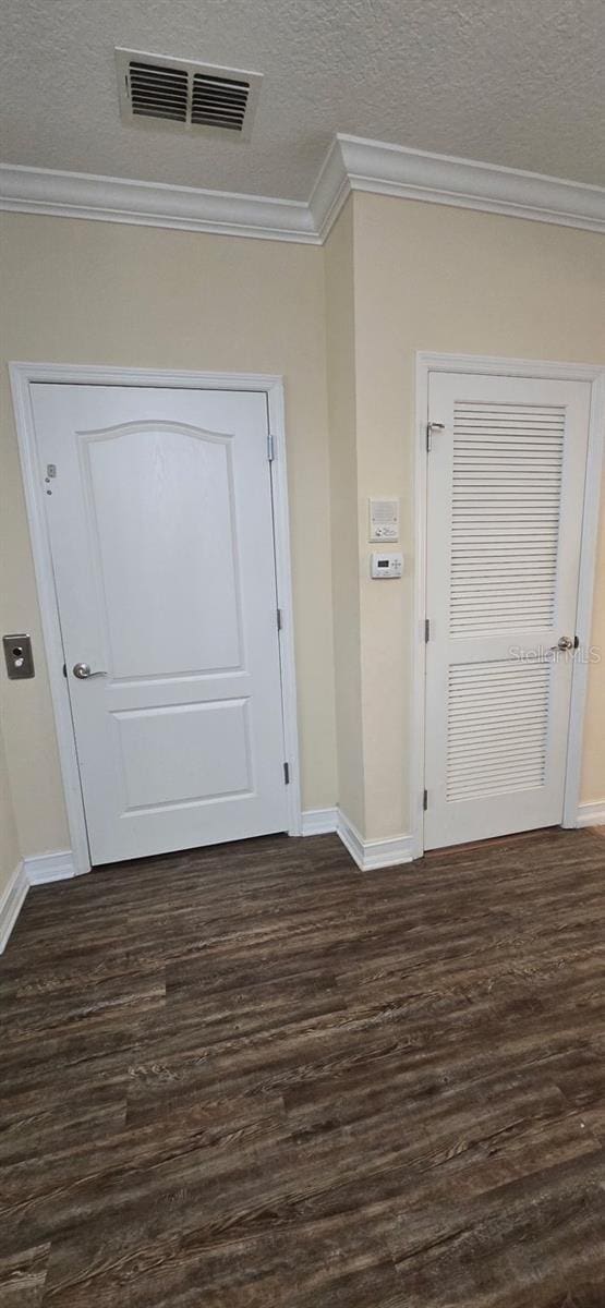 interior space featuring dark wood-type flooring, crown molding, and a textured ceiling