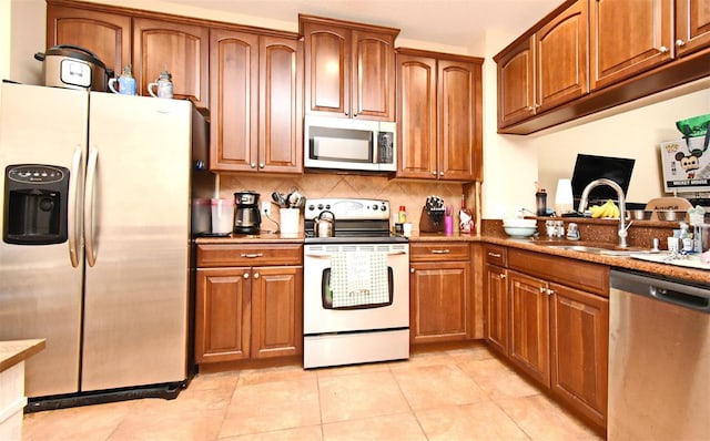 kitchen featuring sink, appliances with stainless steel finishes, tasteful backsplash, light stone countertops, and light tile patterned flooring