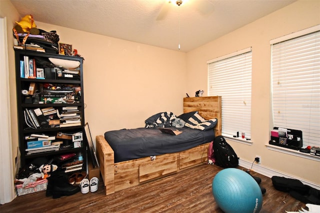 bedroom with dark wood-type flooring, ceiling fan, and a textured ceiling