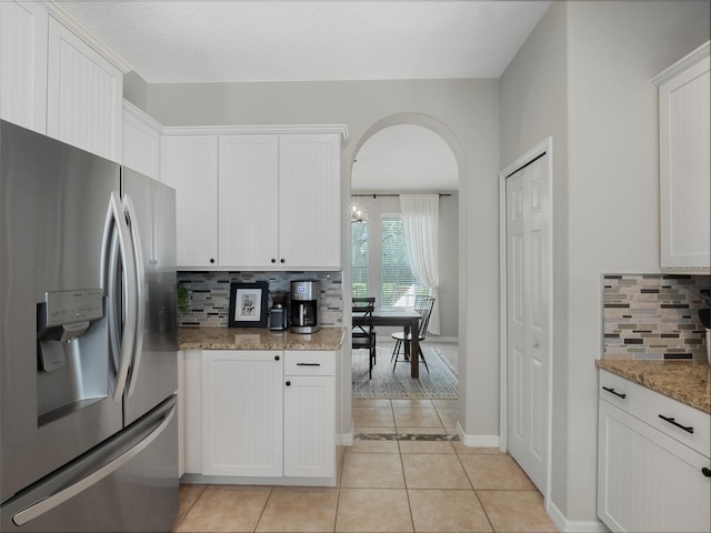 kitchen with stone counters, white cabinetry, and stainless steel fridge