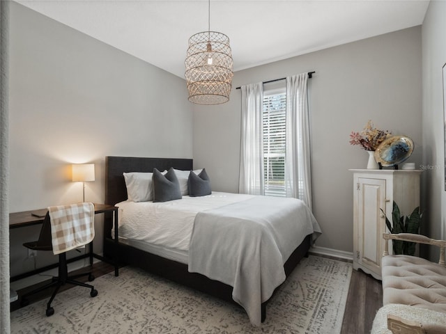 bedroom with wood-type flooring and an inviting chandelier