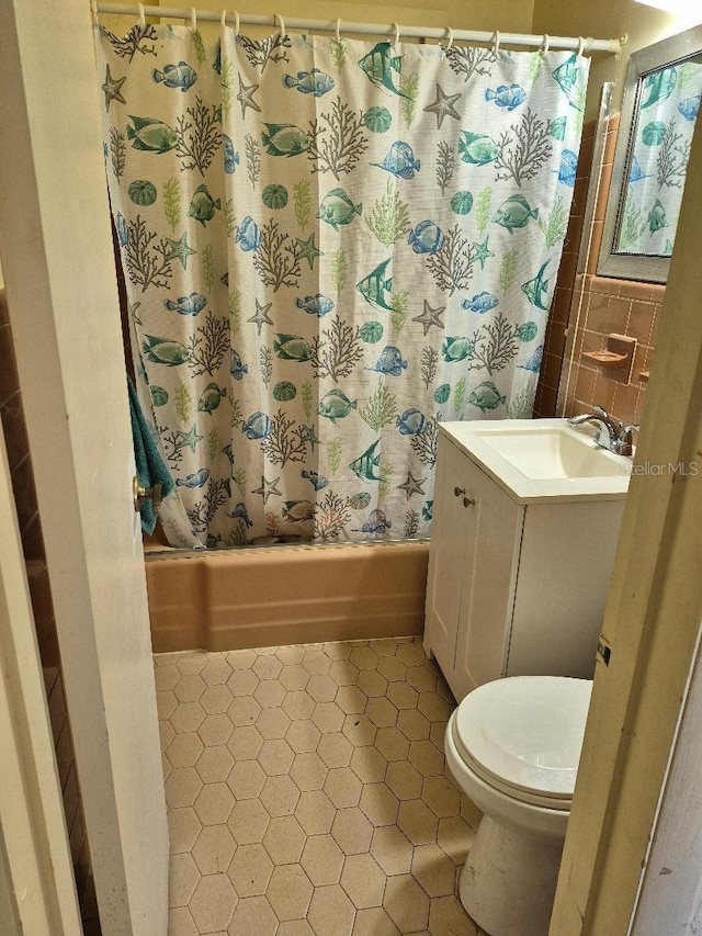 full bathroom with shower / tub combo with curtain, vanity, tile walls, and toilet