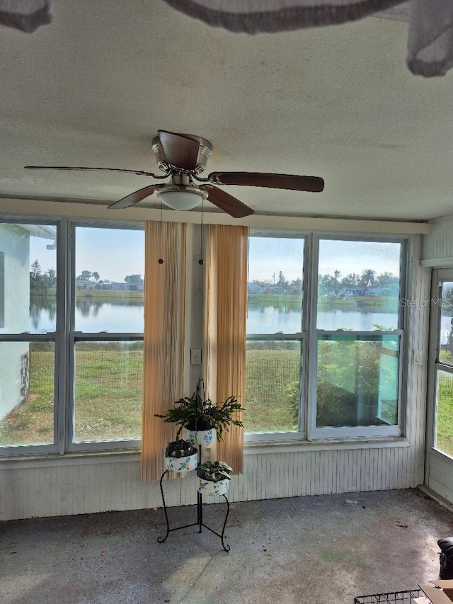 sunroom / solarium featuring ceiling fan and a water view