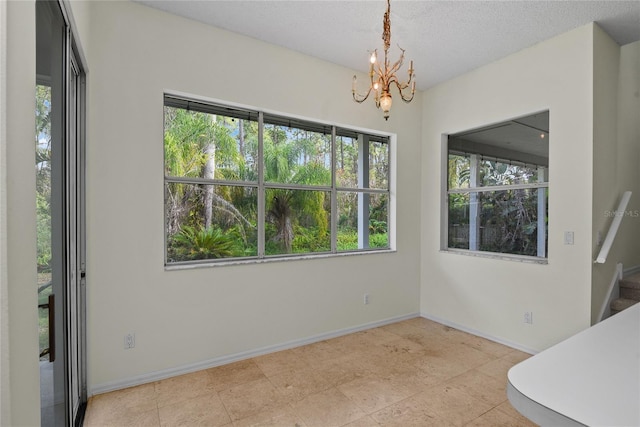 unfurnished dining area with an inviting chandelier and a textured ceiling