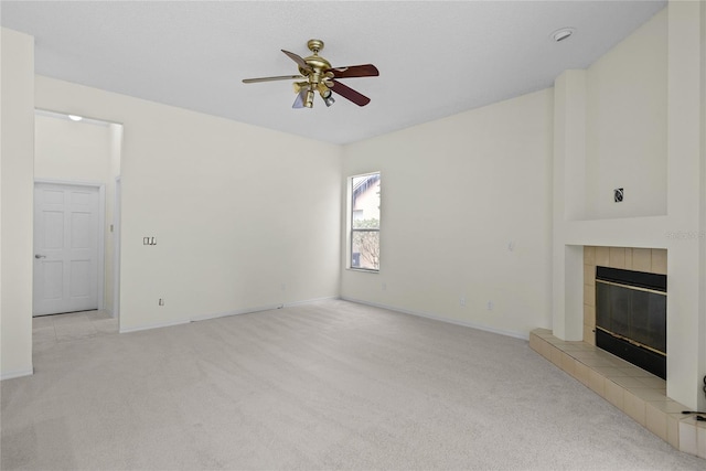 unfurnished living room with a tiled fireplace, light carpet, and ceiling fan