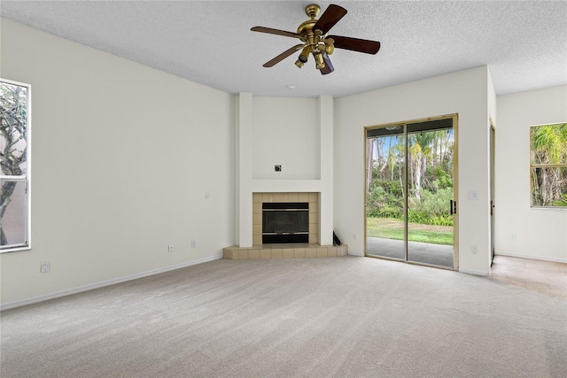 unfurnished living room with a tiled fireplace, ceiling fan, light carpet, and a textured ceiling