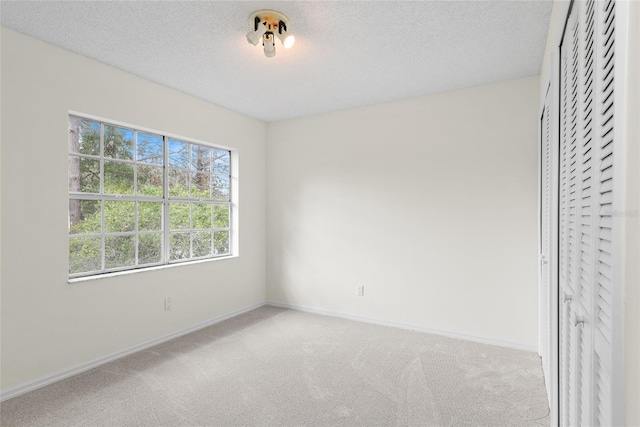 unfurnished bedroom with light colored carpet, a closet, and a textured ceiling