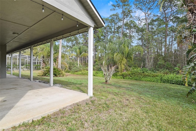 view of yard with glass enclosure and a patio area