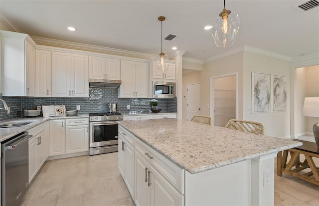 kitchen with appliances with stainless steel finishes, decorative light fixtures, sink, and a kitchen island