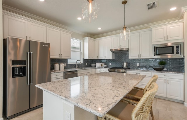 kitchen featuring appliances with stainless steel finishes, sink, white cabinets, a center island, and light stone countertops