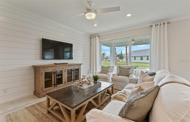 living room featuring wooden walls, ornamental molding, light hardwood / wood-style floors, and ceiling fan