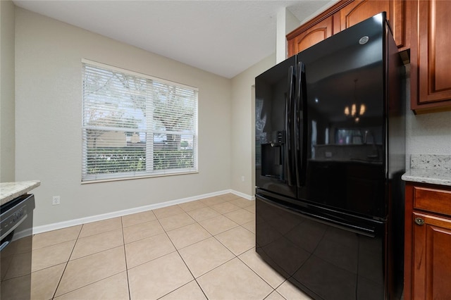 kitchen with light tile patterned floors, light stone counters, and black appliances