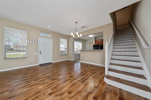 interior space with dark hardwood / wood-style floors, a textured ceiling, and an inviting chandelier