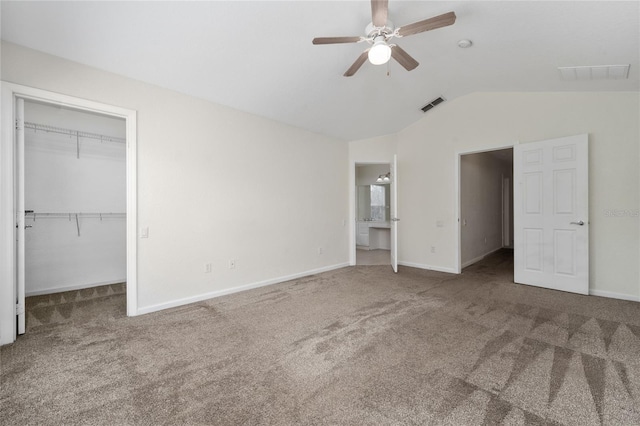 unfurnished bedroom featuring lofted ceiling, ceiling fan, carpet floors, a spacious closet, and a closet