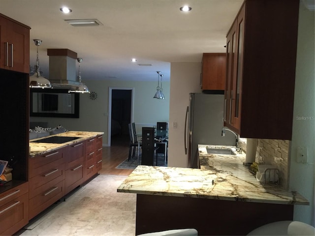 kitchen featuring sink, stainless steel refrigerator, light stone counters, black electric stovetop, and kitchen peninsula