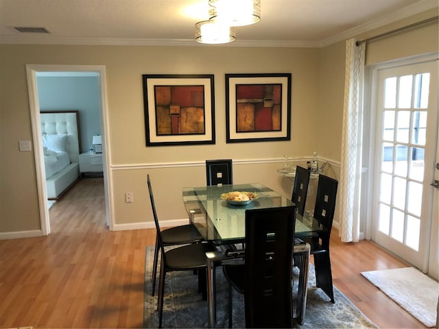 dining room with ornamental molding and light hardwood / wood-style flooring