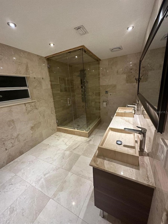 bathroom with vanity, an enclosed shower, tile walls, and a textured ceiling