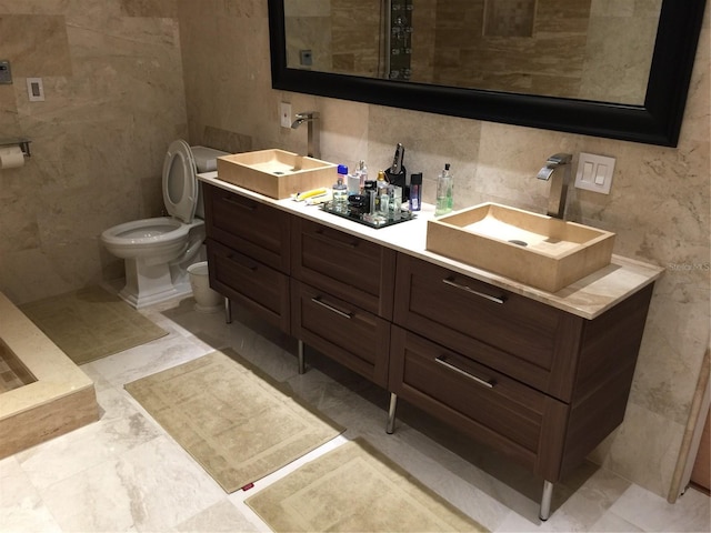 bathroom featuring vanity, tile walls, and toilet