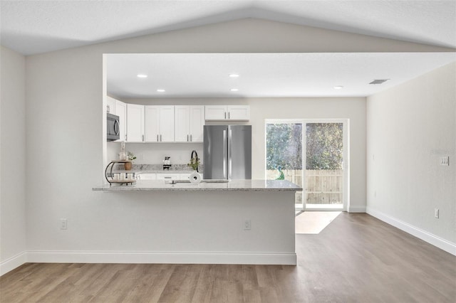 kitchen with stainless steel appliances, light stone countertops, white cabinets, and light hardwood / wood-style flooring