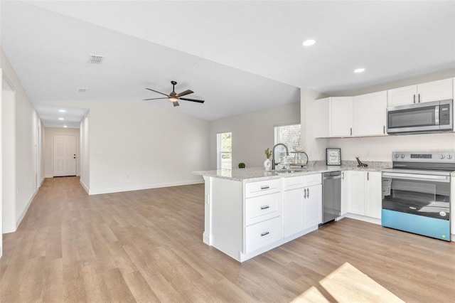 kitchen with sink, stainless steel appliances, light stone countertops, white cabinets, and kitchen peninsula