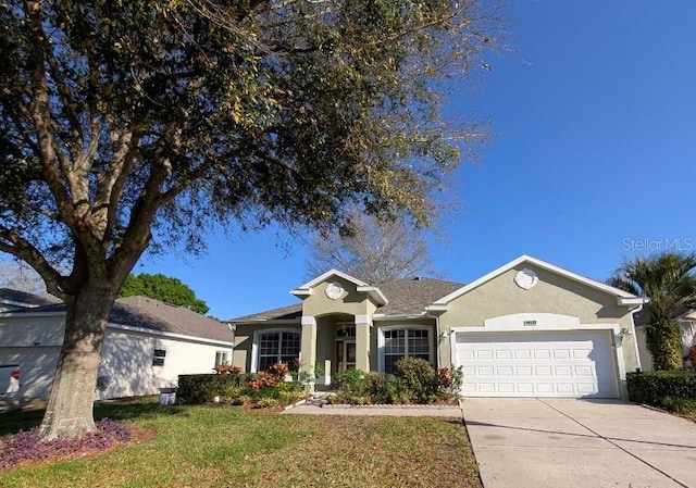 ranch-style house featuring a garage, driveway, a front yard, and stucco siding