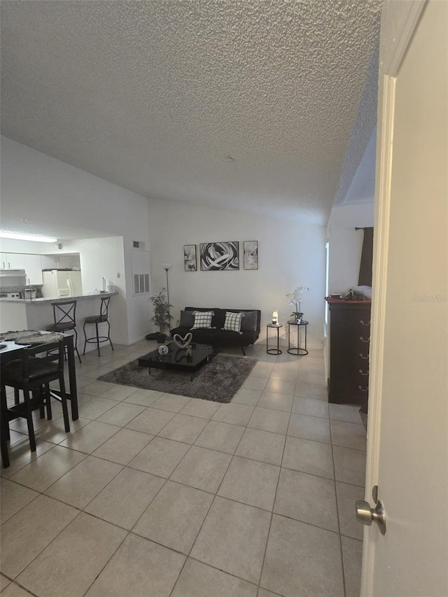 living room featuring vaulted ceiling, a textured ceiling, and light tile patterned floors