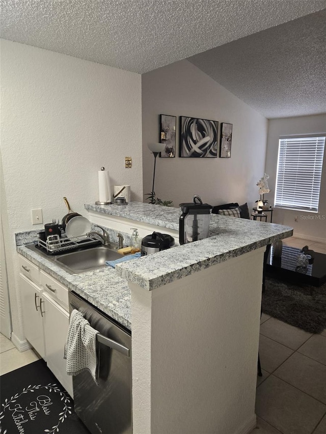 kitchen featuring sink, white cabinetry, light tile patterned floors, stainless steel dishwasher, and kitchen peninsula