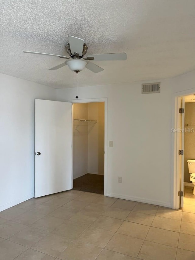 empty room featuring ceiling fan, a textured ceiling, and light tile patterned floors