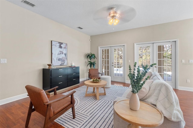 living area with ceiling fan, a textured ceiling, dark hardwood / wood-style flooring, and french doors