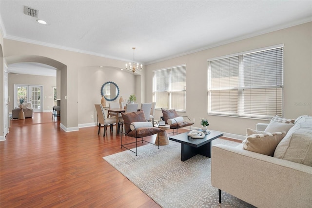 living room featuring an inviting chandelier, hardwood / wood-style flooring, ornamental molding, and a textured ceiling