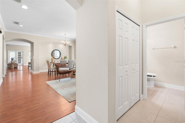 hall with an inviting chandelier, light hardwood / wood-style flooring, and ornamental molding