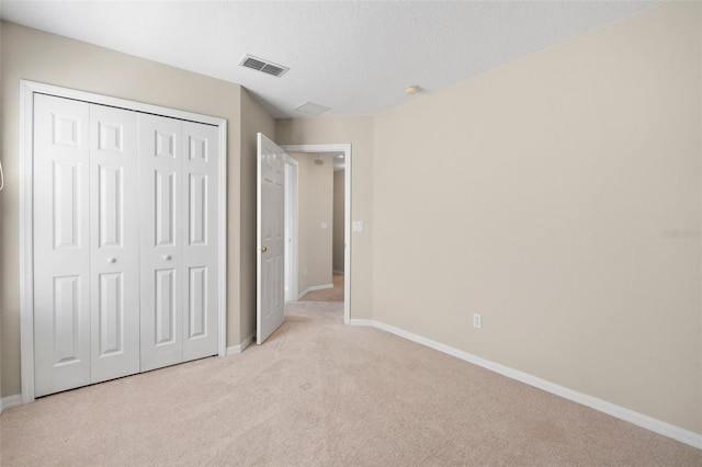 unfurnished bedroom with light colored carpet, a closet, and a textured ceiling