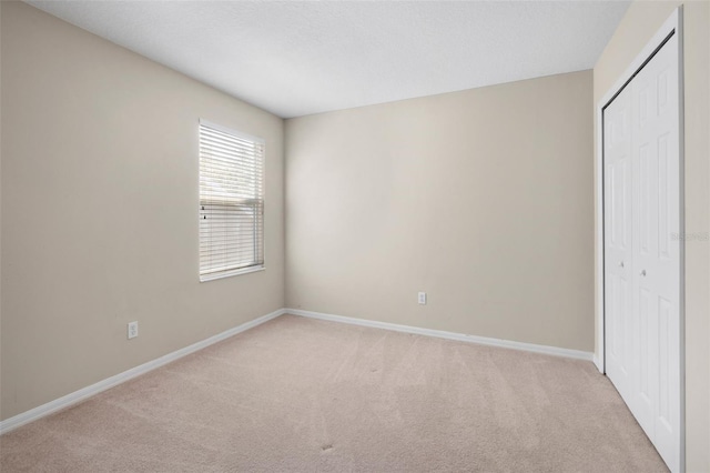 unfurnished bedroom with light carpet and a closet