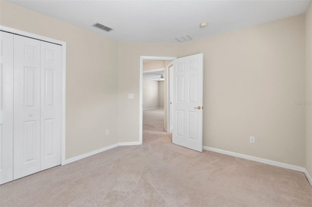 unfurnished bedroom with a closet and light carpet