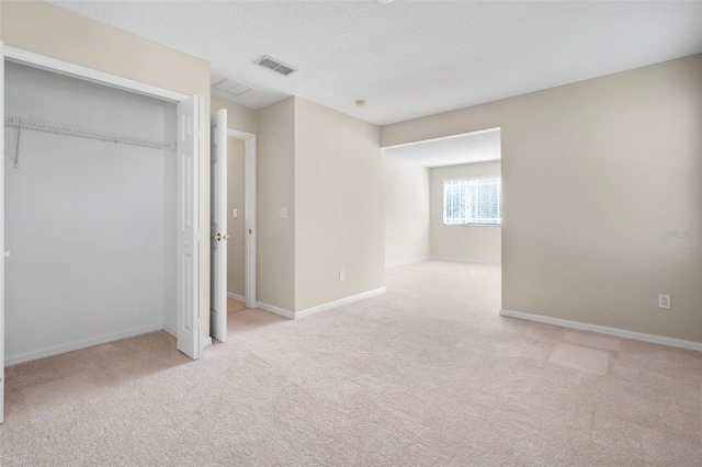 unfurnished bedroom featuring light carpet, a closet, and a textured ceiling