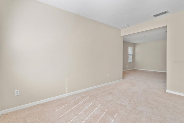 spare room featuring light carpet and a textured ceiling