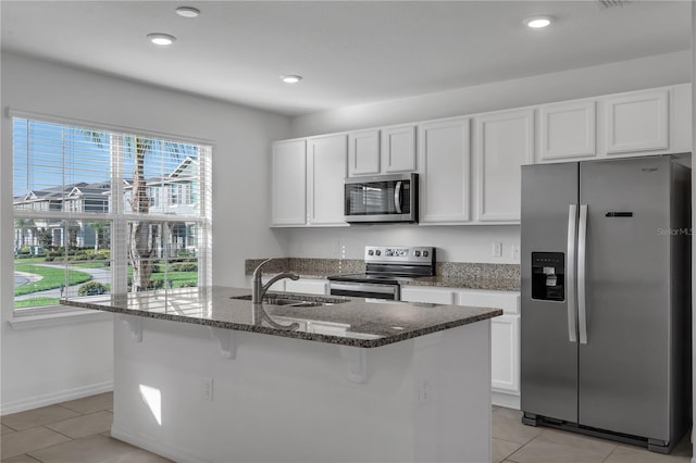 kitchen with white cabinetry, stainless steel appliances, sink, and a center island with sink