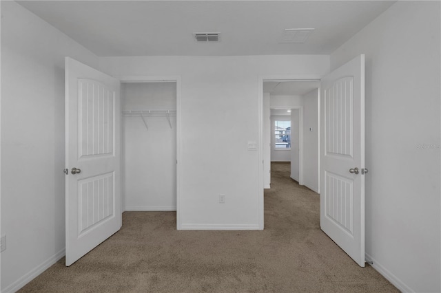 unfurnished bedroom featuring light carpet and a closet