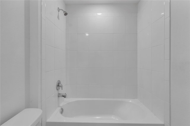 bathroom featuring toilet and tiled shower / bath combo