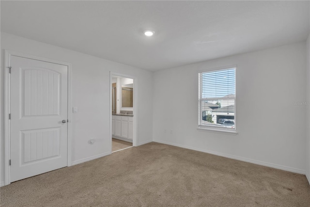 unfurnished bedroom with ensuite bath and light carpet