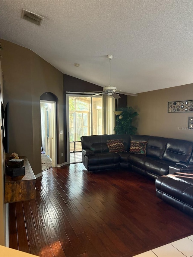 living room featuring hardwood / wood-style flooring, lofted ceiling, and a textured ceiling