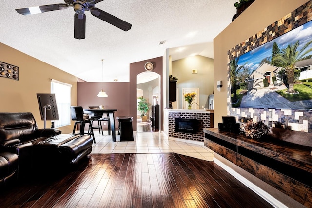 living room featuring light wood-type flooring, lofted ceiling, a textured ceiling, and a fireplace