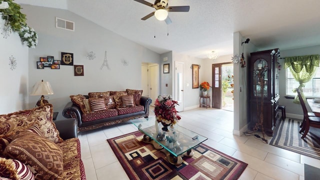 living room featuring lofted ceiling, ceiling fan with notable chandelier, a textured ceiling, and light tile patterned floors