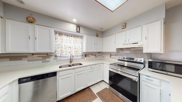 kitchen featuring under cabinet range hood, a sink, white cabinetry, appliances with stainless steel finishes, and decorative backsplash