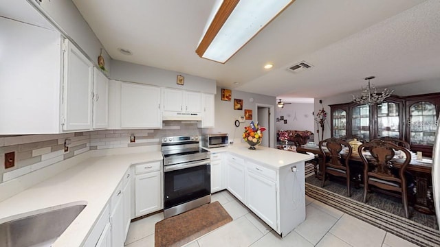 kitchen featuring tasteful backsplash, light tile patterned floors, kitchen peninsula, stainless steel appliances, and white cabinets