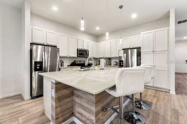 kitchen with pendant lighting, sink, a breakfast bar area, white cabinets, and stainless steel appliances